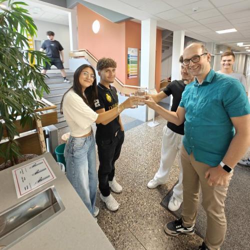 Schüler:innen stoßen mit Wassergläsern mit dem Schulleiter an