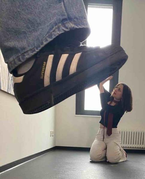 Frau scheint unter einem Fuß zertreten zu werden, sie ist in Abwehrhaltung