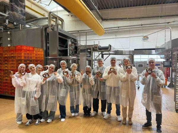 Klasse in Schutzanzügen mit Brezeln in der Hand 