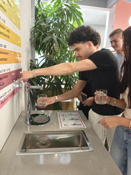 Schüler füllt sich sein Glas mit Wasser am Spender